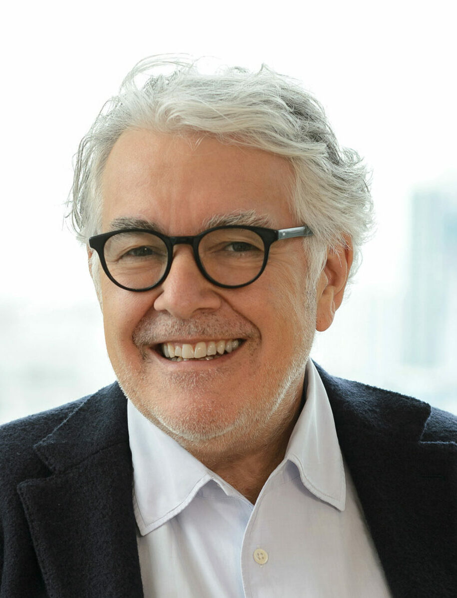 A headshot of Neil Jacobs, CEO, Six Senses Resorts Hotels and Spas, a man with grey hair and an open-neced shirt