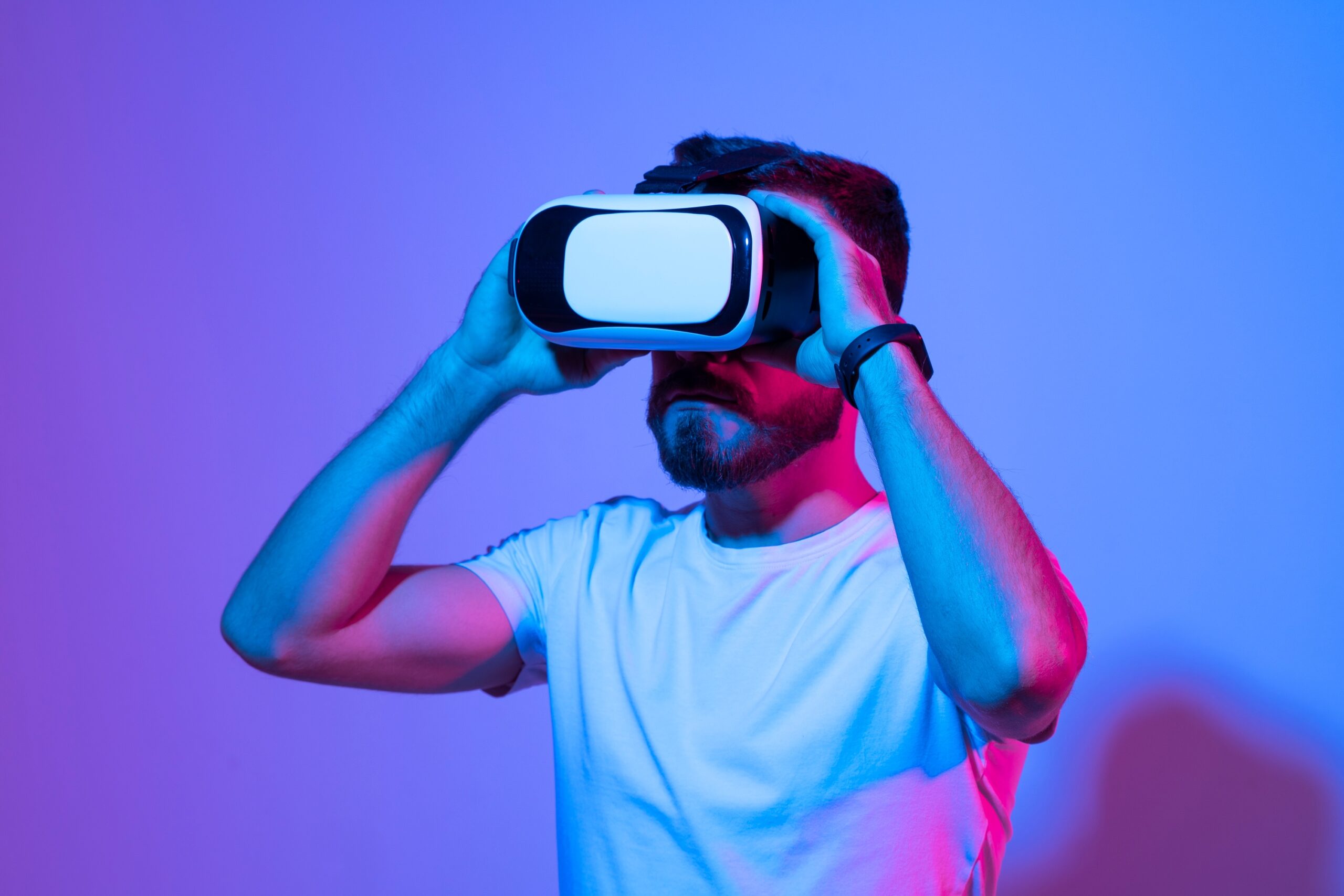 Picture of a man bathed in purple light and wearing a virtual reality headset