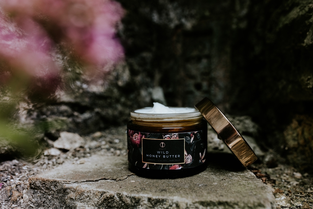 Tribe517's Honey Duo Wild Honey Butter on concrete with flowers in the foreground