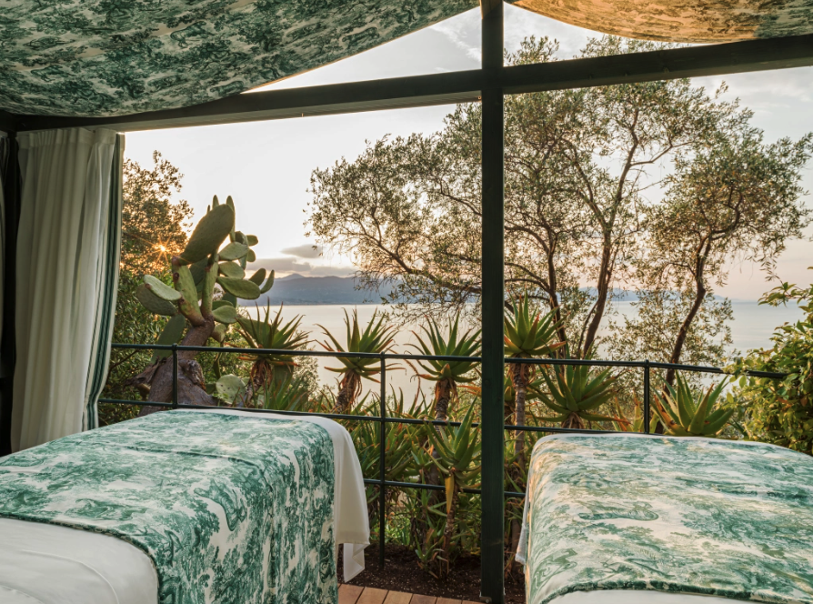 Two spa beds, dressed in Dior's Toile de Jouy Fabric, in front of a stunning view with trees and sea ©Kristen Pelou