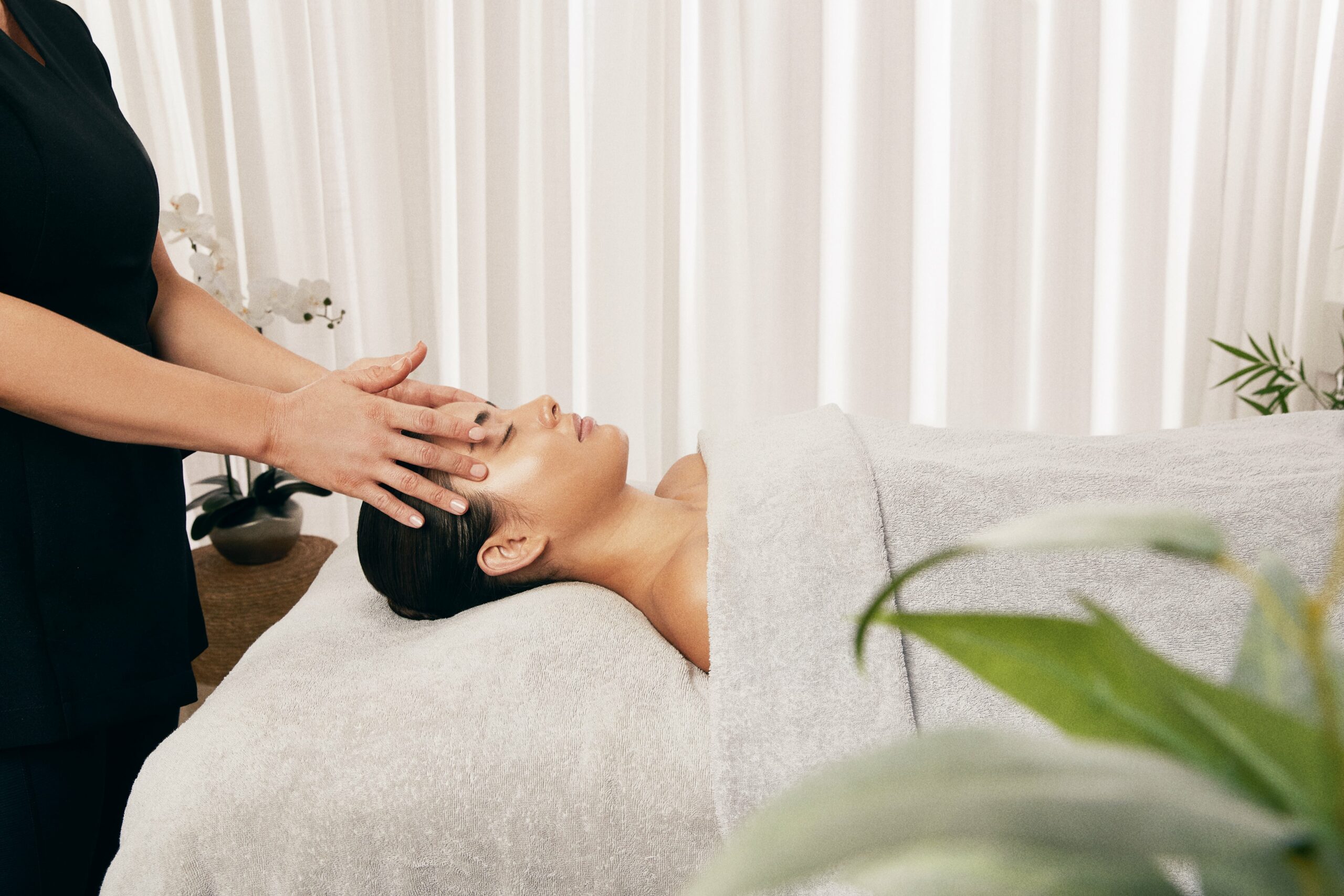 A woman on a spa bed receiving a facial from a spa therapist