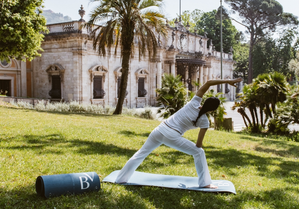A woman doing yoga on the lawn in front of the Palazzo BelVedere hotel