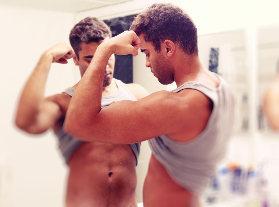 A men flexing his muscles in the mirror