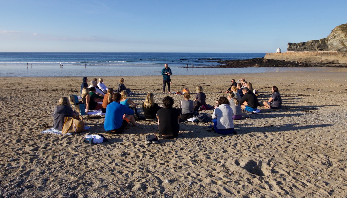 group of people meditating on the beach