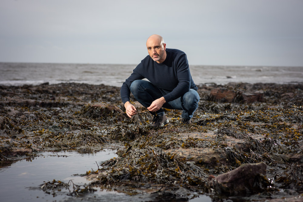Doctor Seaweed – Dr Craig Rose on rocks with seaweed