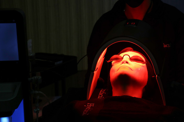 person under a red LED light having facial