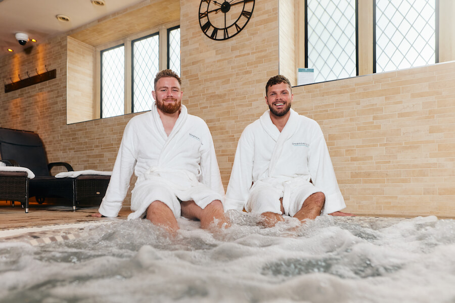 Men in spa robes sitting beside a jacuzzi