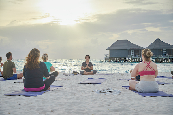 people meditating on the beach in the Maldives