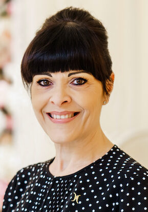 Woman smiling at camera wearing black spotty dress