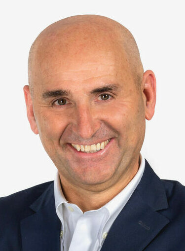 man wearing blue suit and white shirt smiling at camera