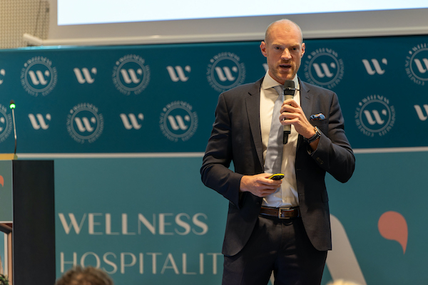 man speaking at a conference at the Wellness Hospitality Conference
