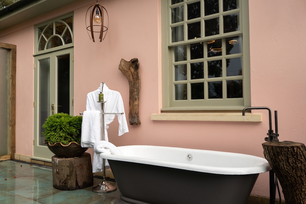 an outdoor bath against a pink wall