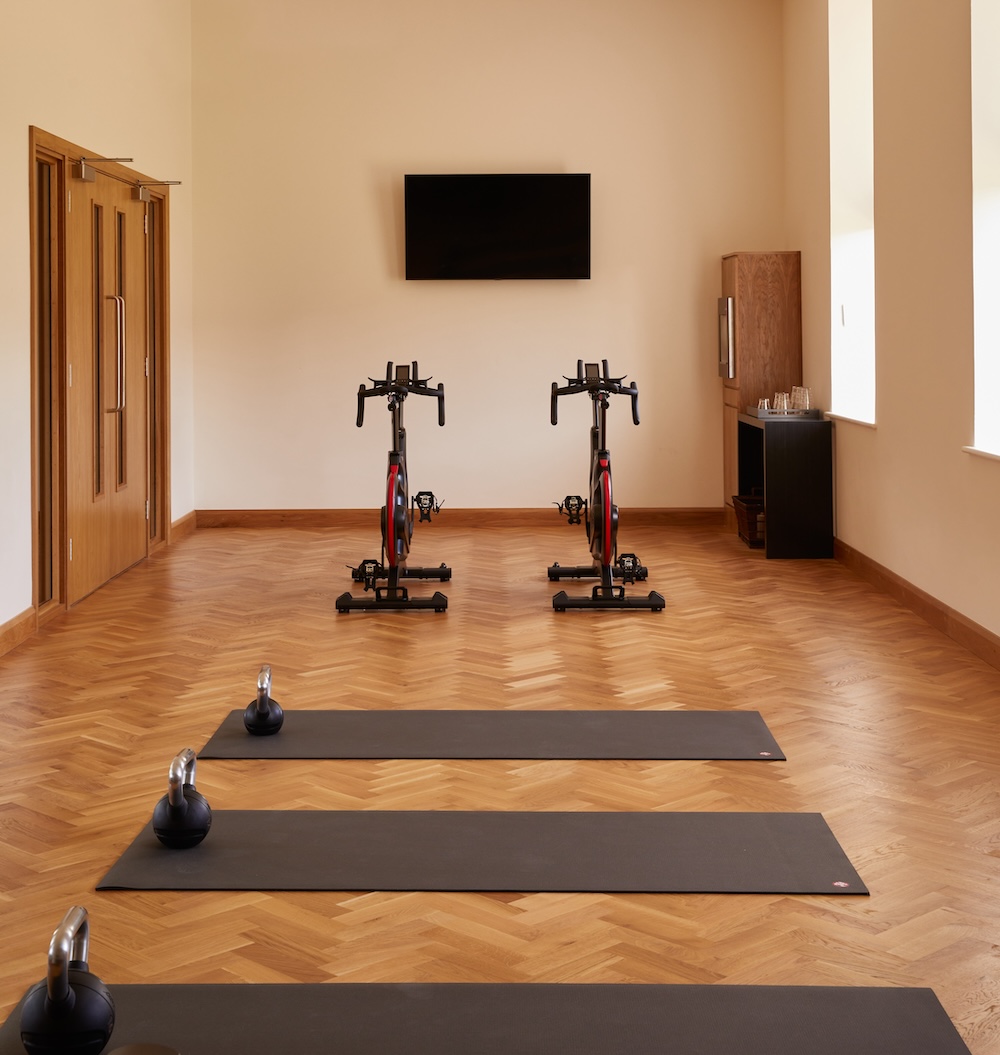 A room with two exercise bikes, mats and weights