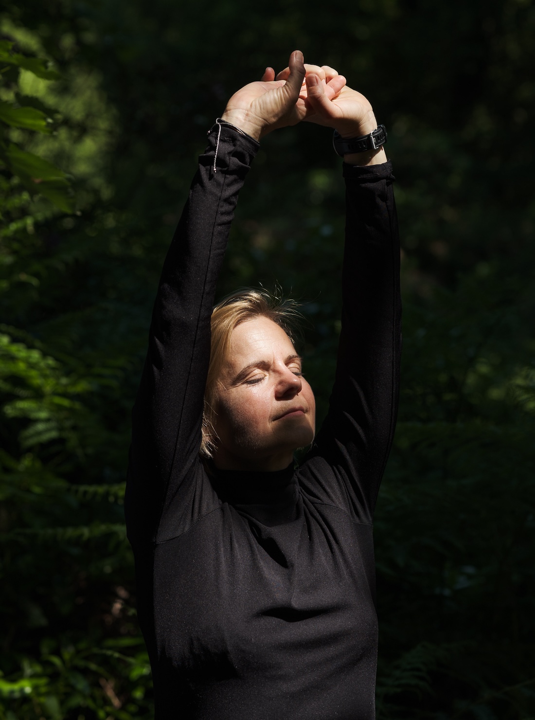A woman in black stretching hands above head