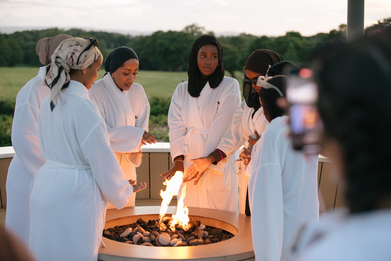 Women in bathrobes stood around a fire