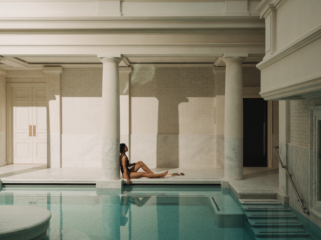 Model sitting against a pillar next to a pool
