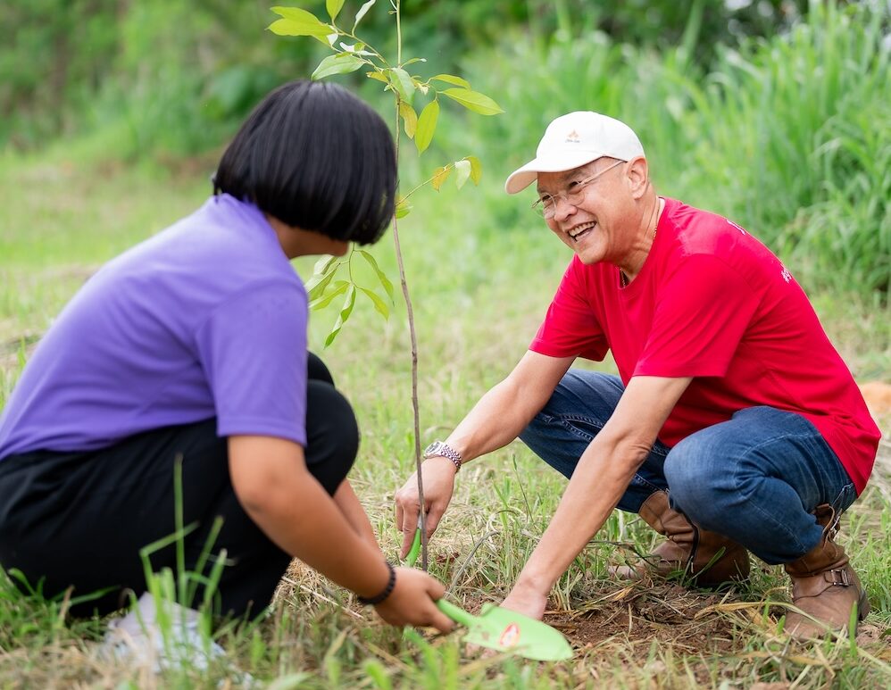 Man and woman crouched planting a tree