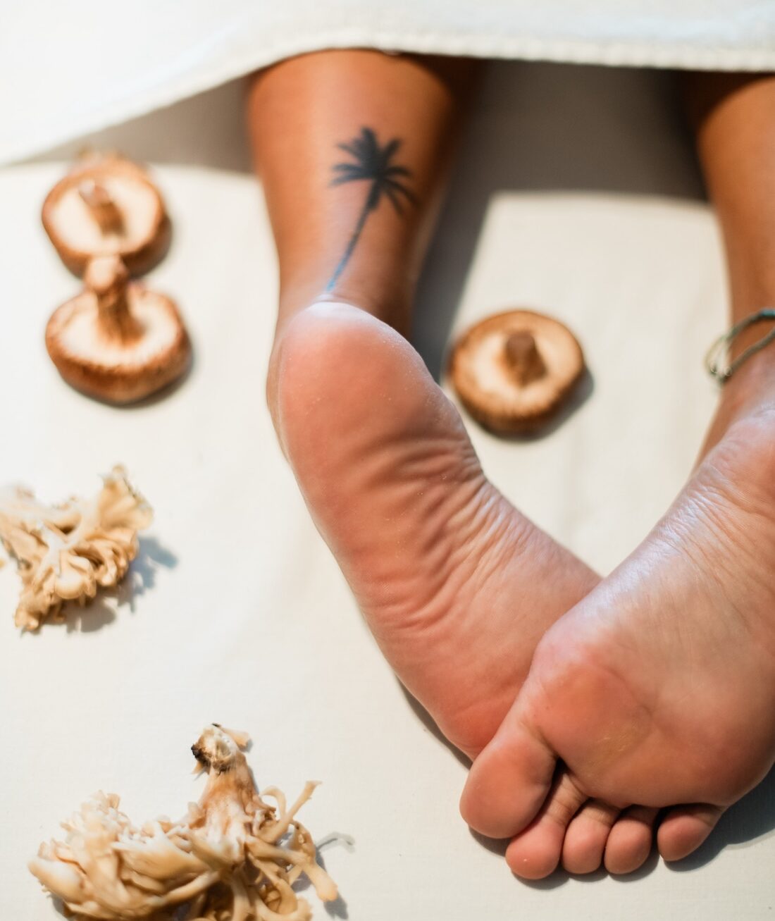 Feet on sand, surrounded by mushrooms