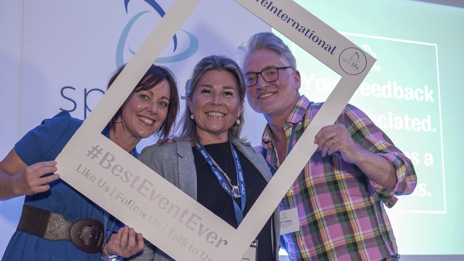 Man and two women smiling through selfie frame