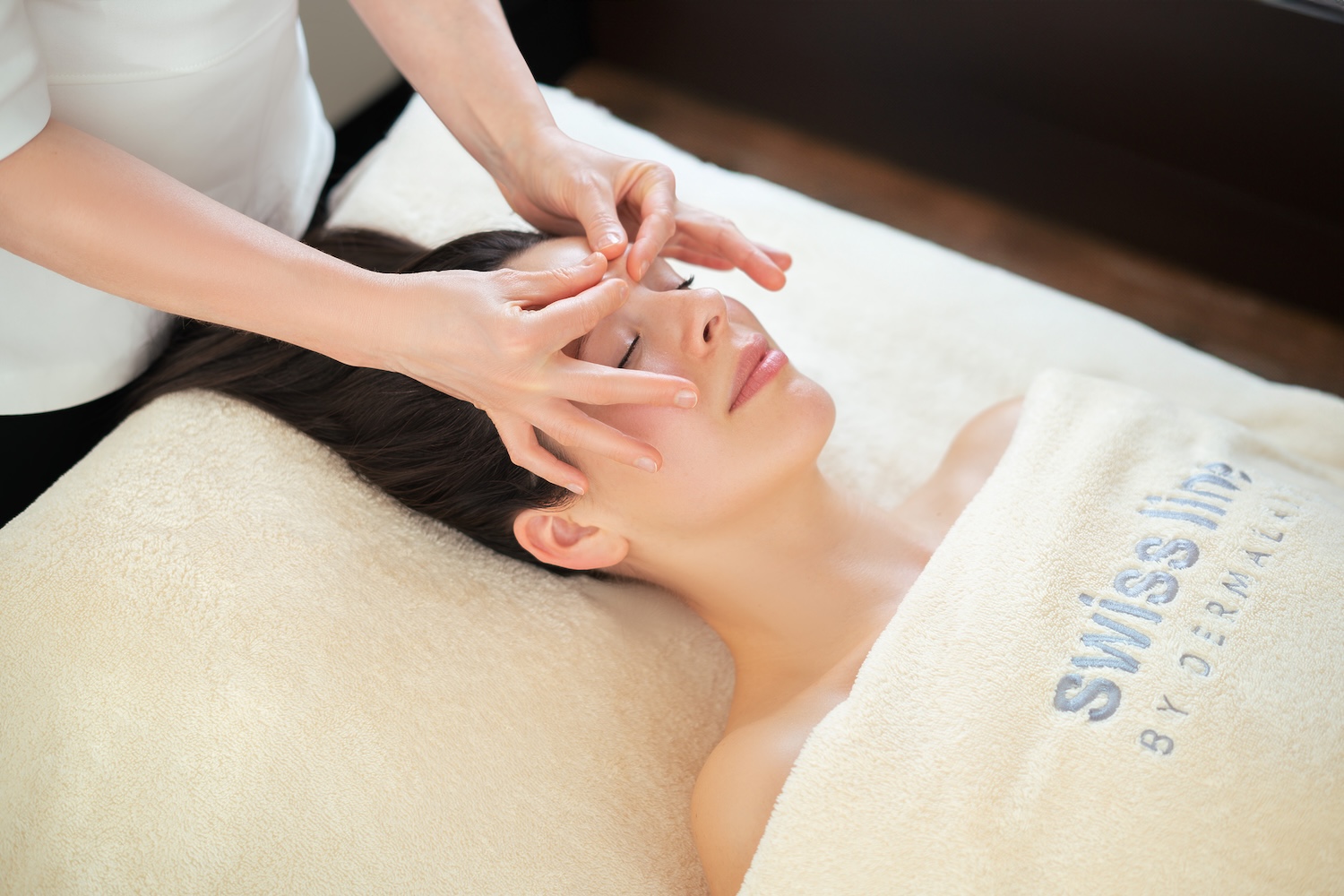 Woman on treatment bed having facial massage