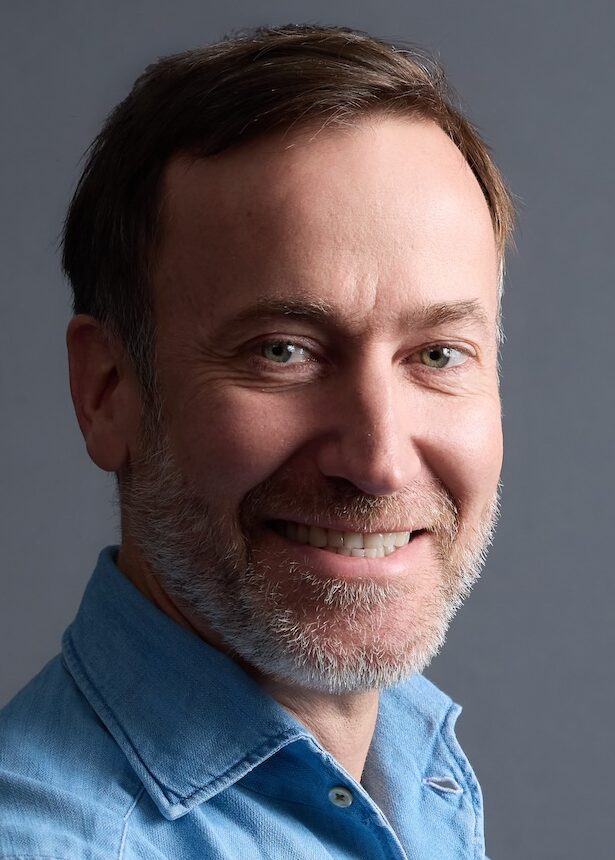 Headshot of man in blue shirt with beard