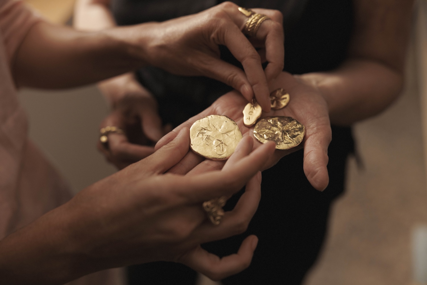 Two pairs of hands holding gold coins