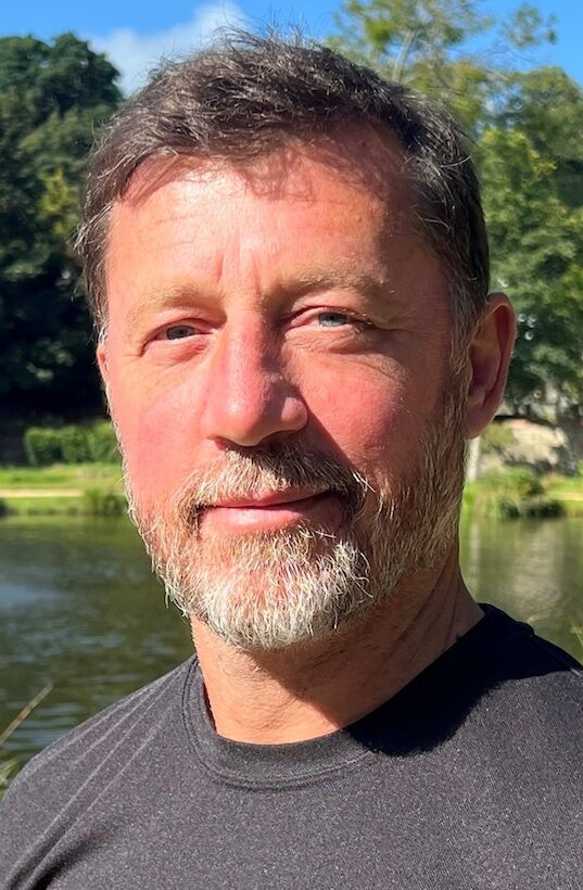 Man with beard stood in front of fountain in sunshine