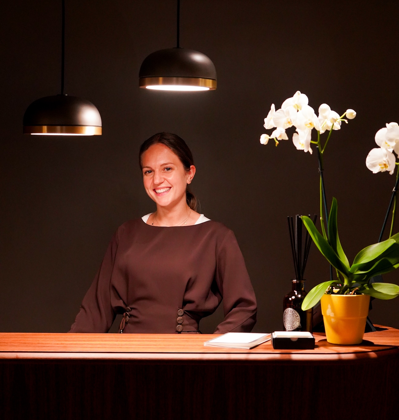 A smiling woman standing behind a reception desk