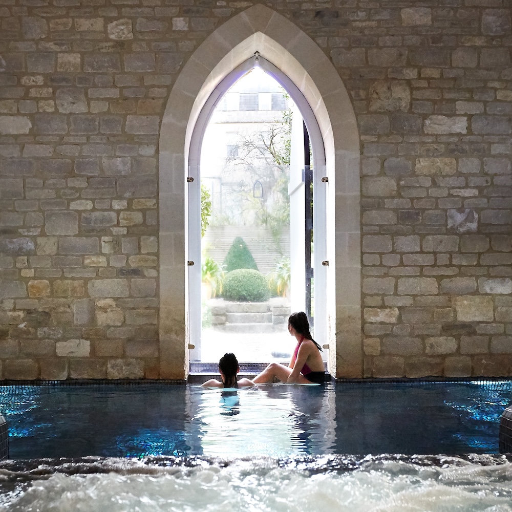 Two people sat in a pool looking out of a church like window