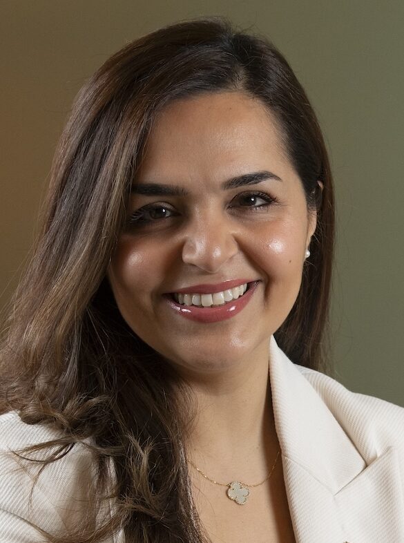 Smiling woman in white suit jacket sat on a sofa