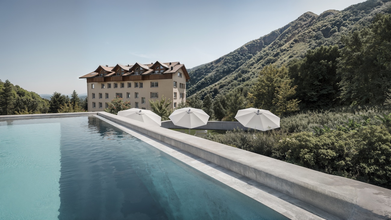 A pool in the mountains by a grand hotel