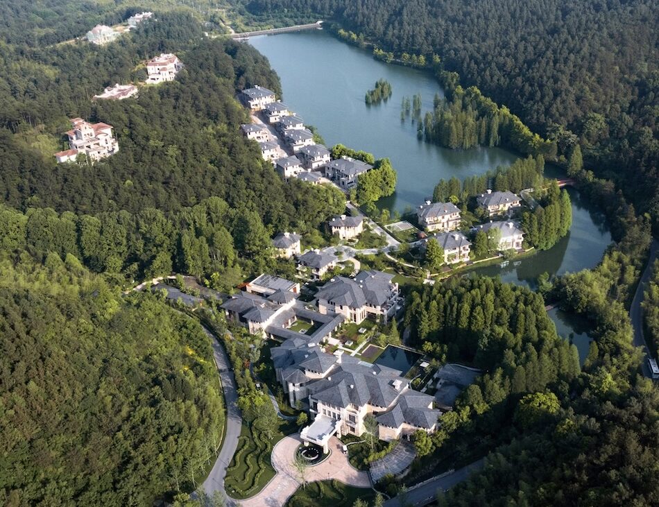 A view of a hotel situated amongst forest on a lake