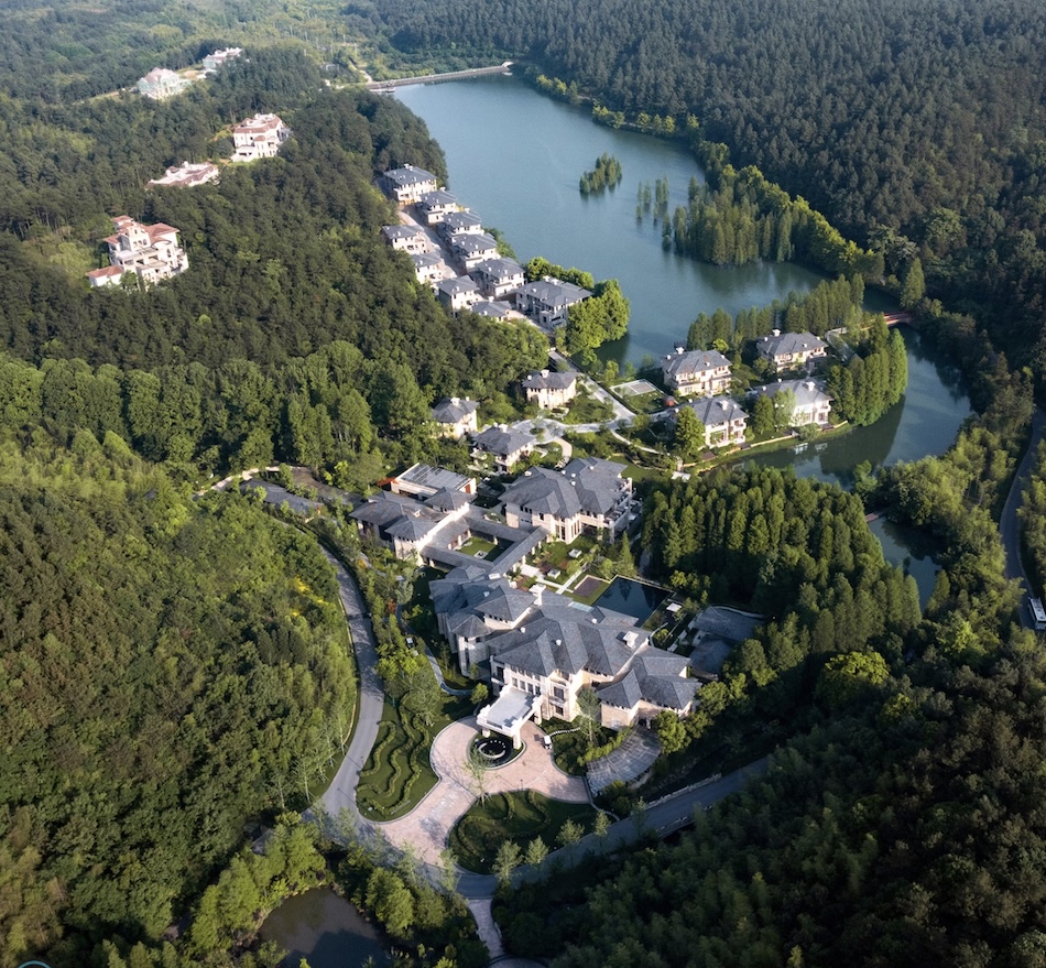 A view of a hotel situated amongst forest on a lake