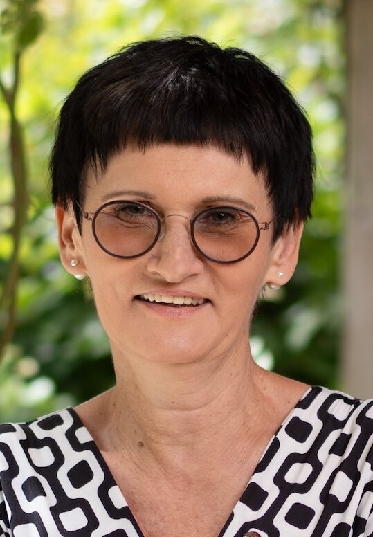 Short haired woman with arms folded, looking at the camera