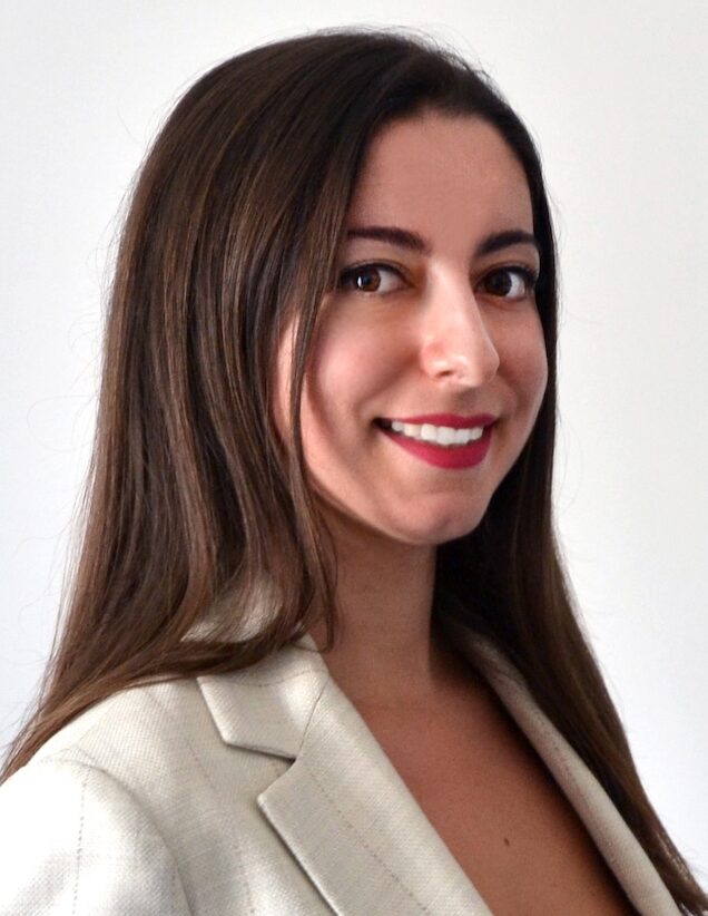 Dark haired woman in white suit jacket smiling