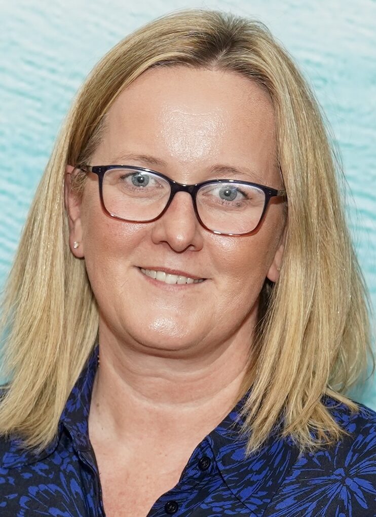 Blonde woman with glasses in blue shirt