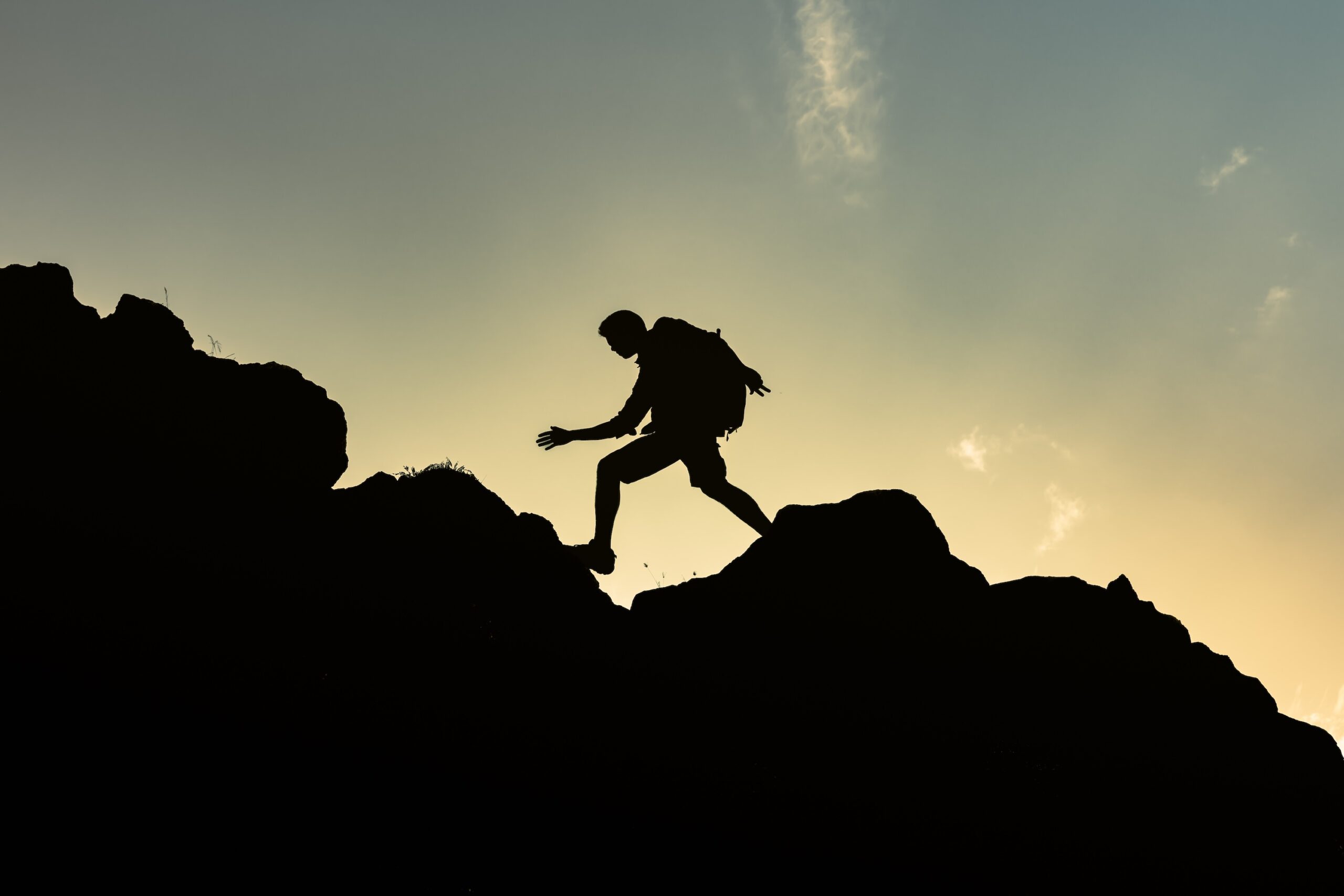 Person climbing a mountain at sunset