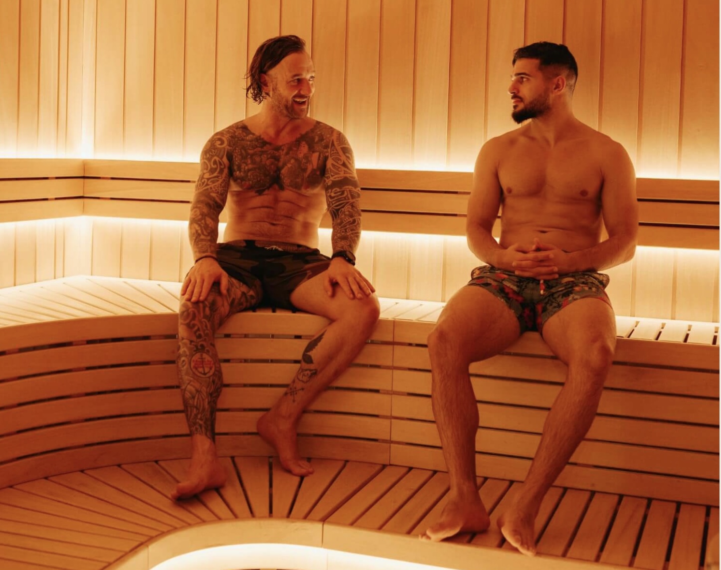 Two men sat in a red lit sauna