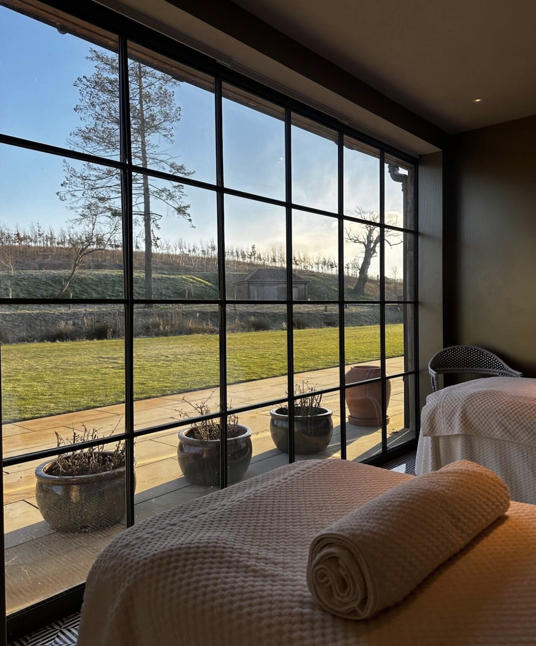 A treatment room with floor to ceiling windows overlooking a sunlit garden