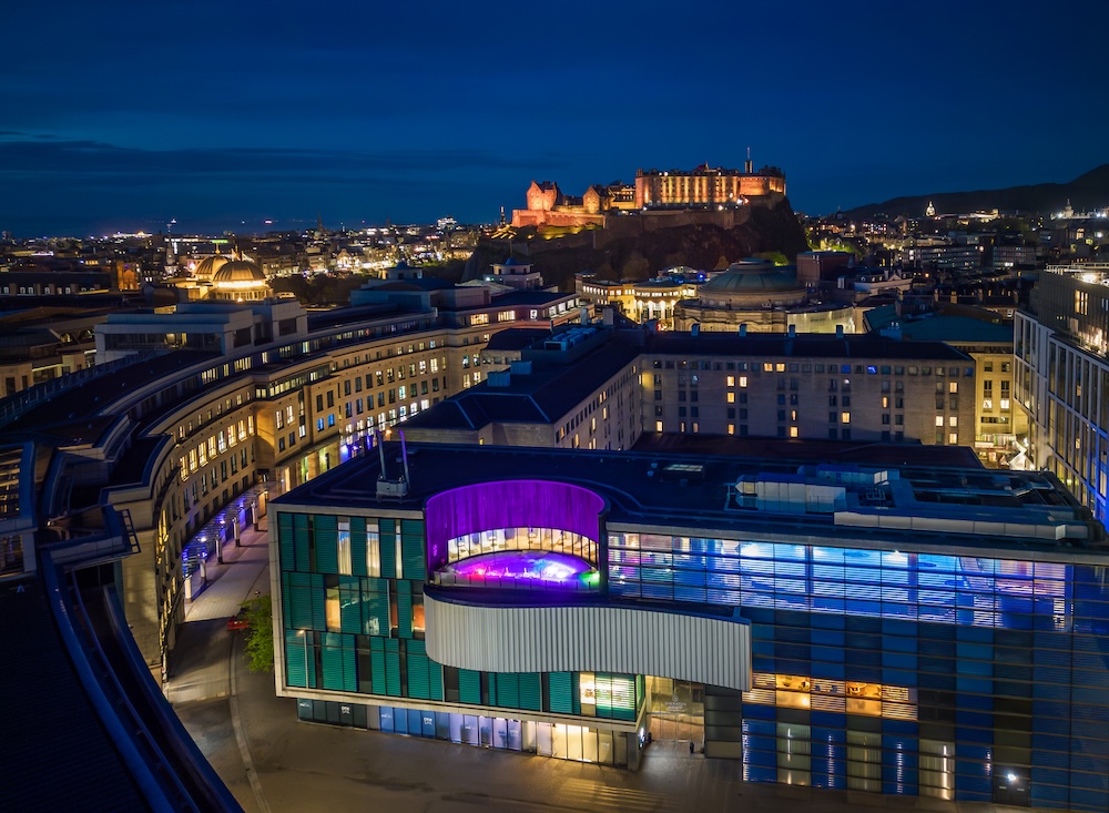 An aerial view of a Scottish hotel with a rooftop hydropool at night