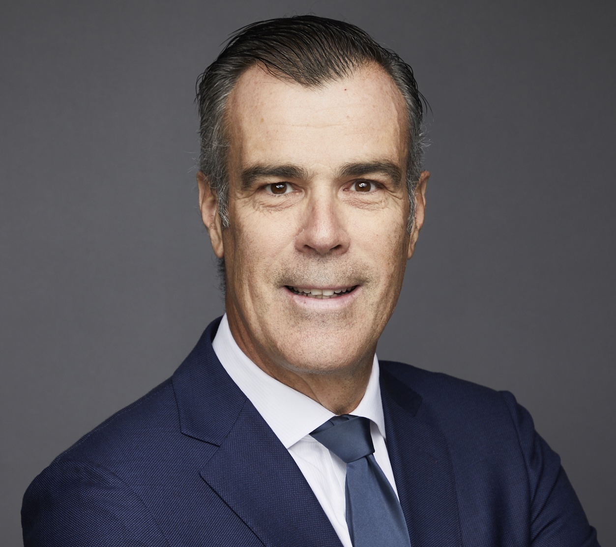 Headshot of man with brown hair in blue suit and tie