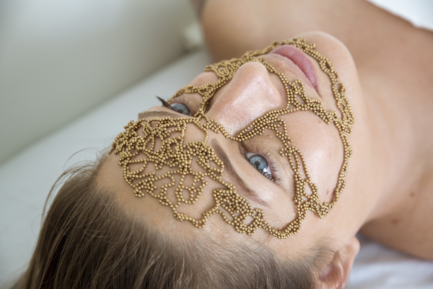 A woman with gold beads positioned on her face