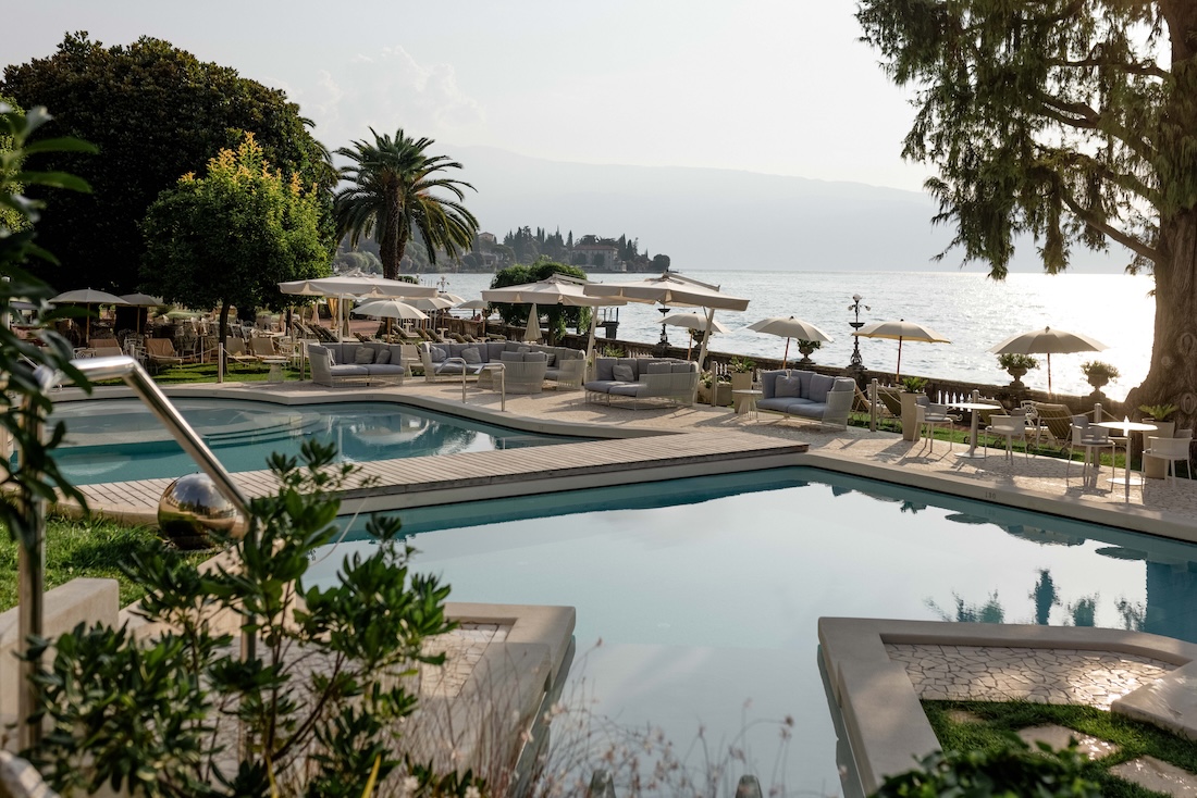 A hotel pool in the sunshine overlooking a lake