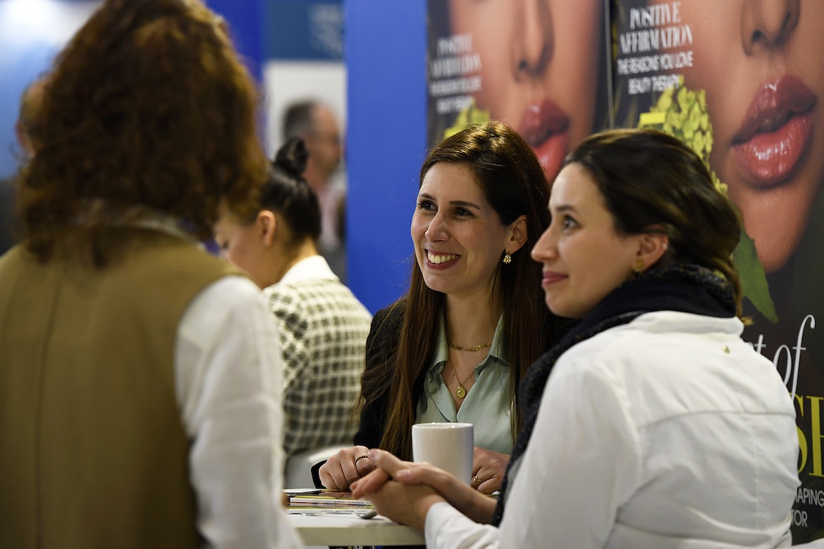 Two women talking to a third in a business convention setting