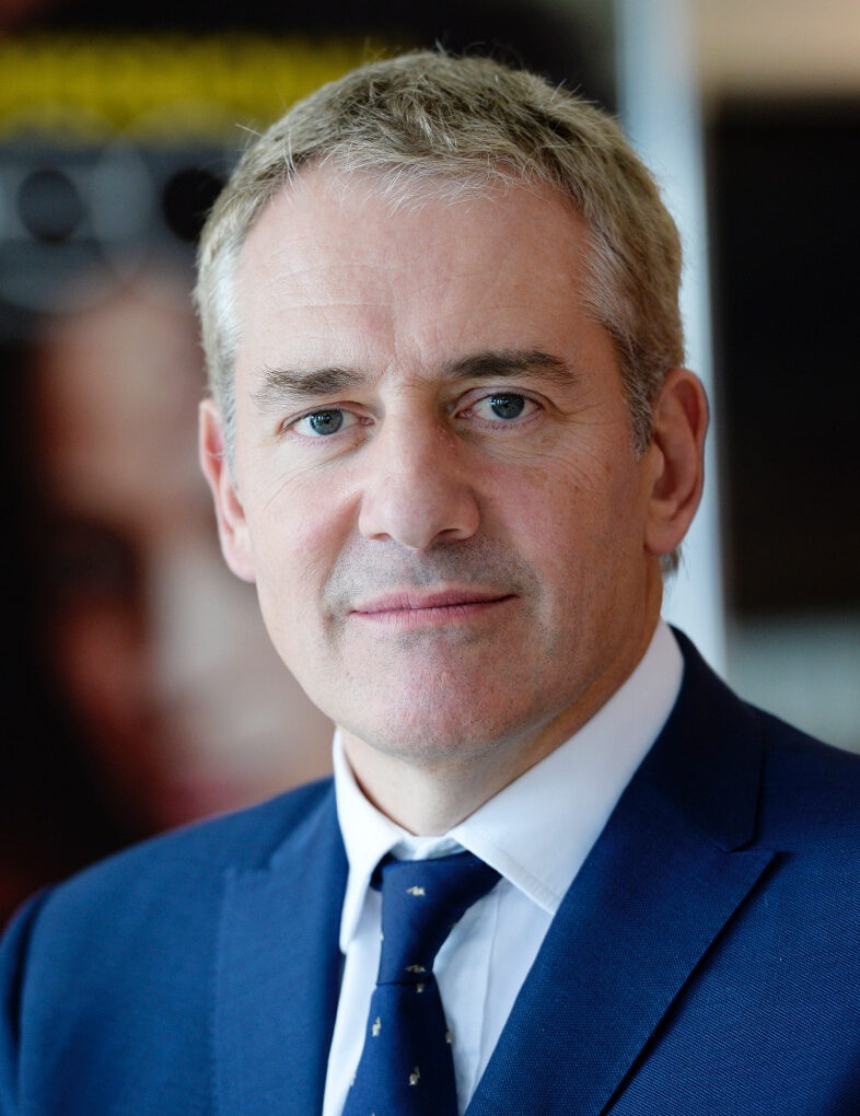 Headshot of a man with grey hair in blue suit and tie