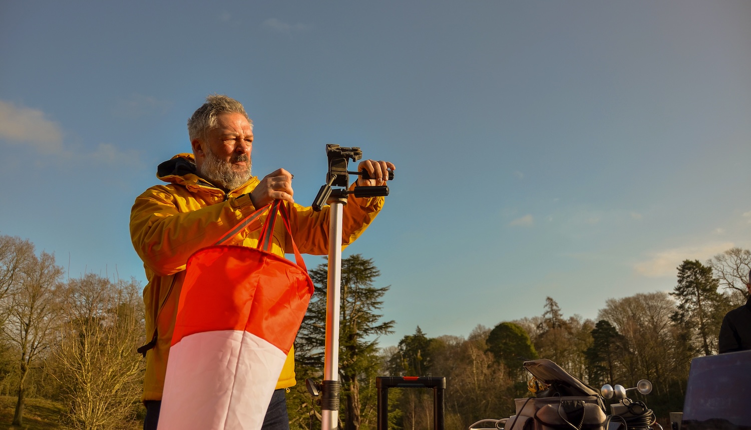 Man using technical devices stood against a blue sky