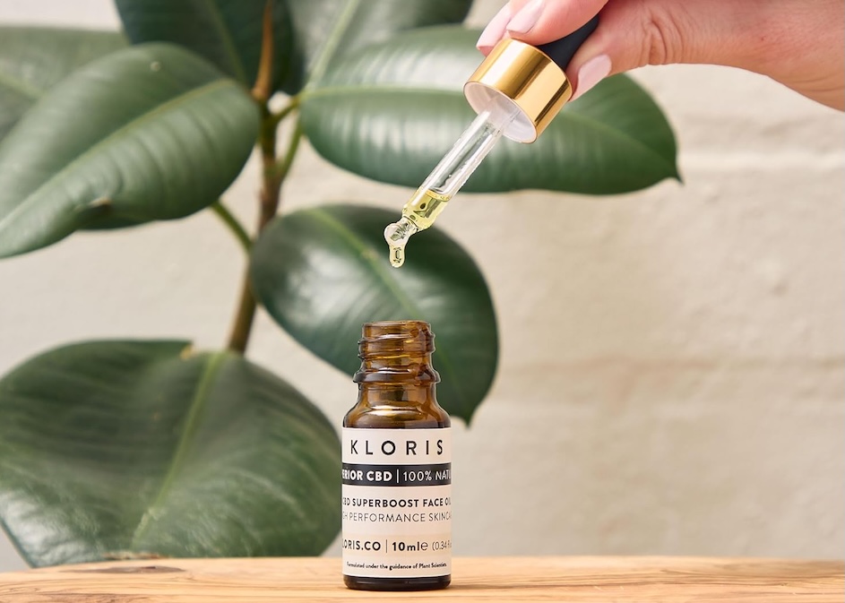 Bottle of CBD oil with female hand holding the dropper
