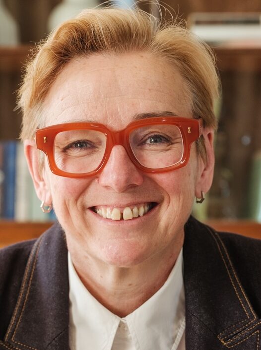 Headshot of smiling woman in bright red glasses