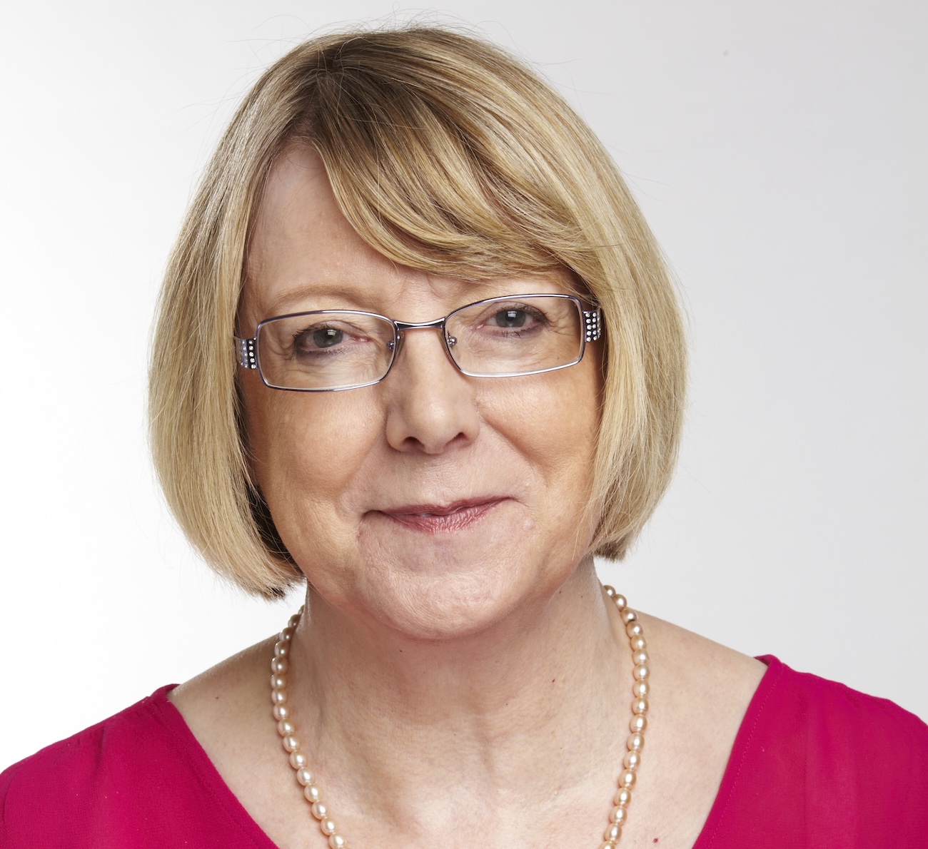 Woman with short blonde hair and glasses wearing bright pink