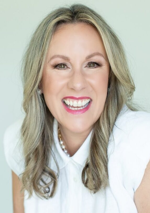Smiling woman with blonde hair in white short sleeved top